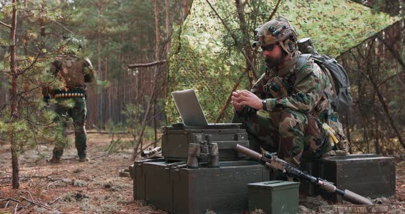 A Bearded Commander in a Military Uniform in a Tactical Vest with a Helmet on His Head Chatting