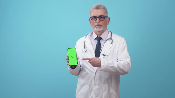 Adult doctor in glasses and medical uniform show app on the phone screen.