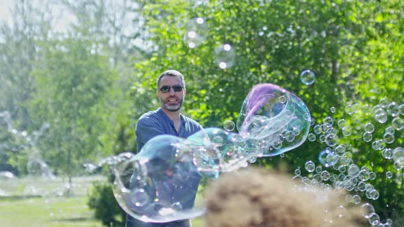 Joyous Man Blowing Large and Small Bubbles for Kids alt