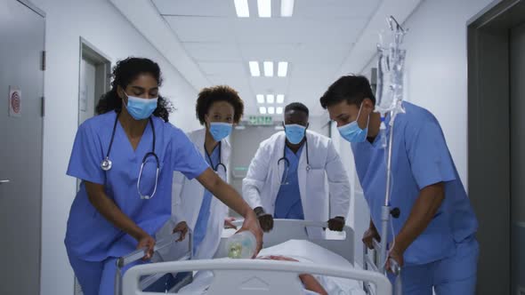 Diverse female and male doctors wearing face mask transporting patient