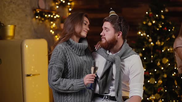 Young Couple Talking on New Year Eve Against Backdrop of Festive Christmas Tree