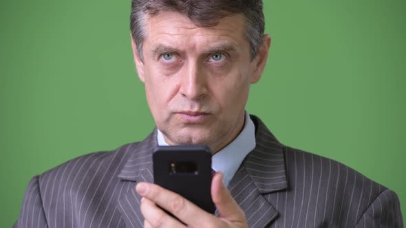 Mature Handsome Businessman Against Green Background