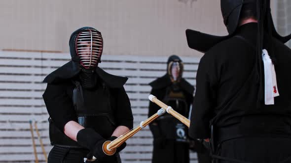 Kendo Tournament in the Gym  Two Men in Black Costumes About to Start a Duel on Bamboo Sticks