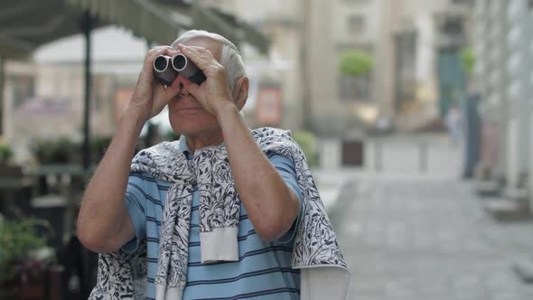 Senior Man Tourist Exploring Town. Looking in Binoculars. Travel Lviv, Ukraine