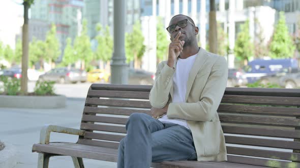 Pensive African Man Thinking While Sitting Outdoor on Bench