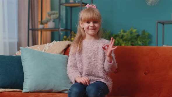 Portrait of Little Child Girl Kid Alone on Sofa at Home Showing Ok Gesture Like Sign Positive Good