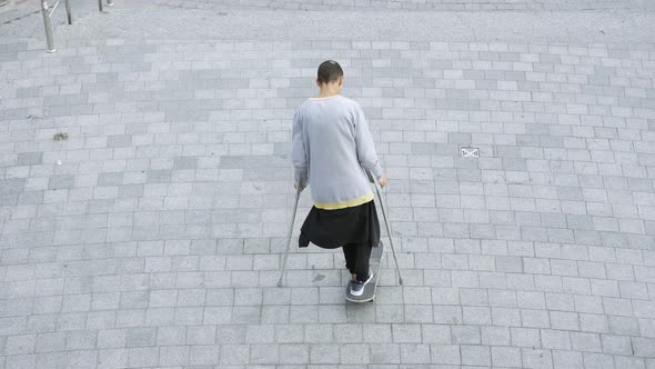 Top View of the Skill Man with One Leg on Crutches Spinning on His Skateboard Doing Tricks