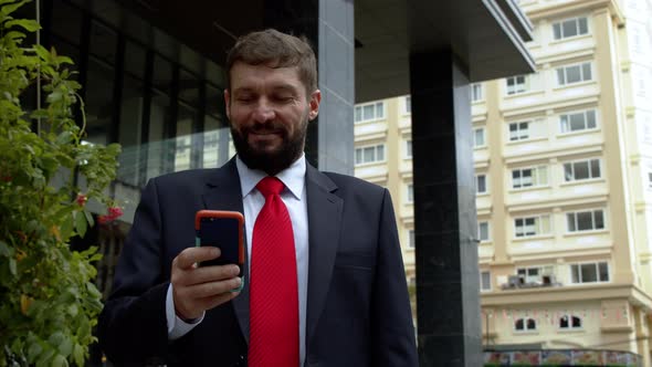 A Business Man Texting Phone in the Street