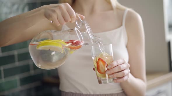 Close Up of Slim Woman with Fruit Detox Water in Glass Bottle