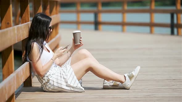 Cute Woman Is Reading Text Message on Mobile Phone While Sitting in the Park.