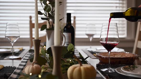 woman pouring wine at Thanksgiving dinner table