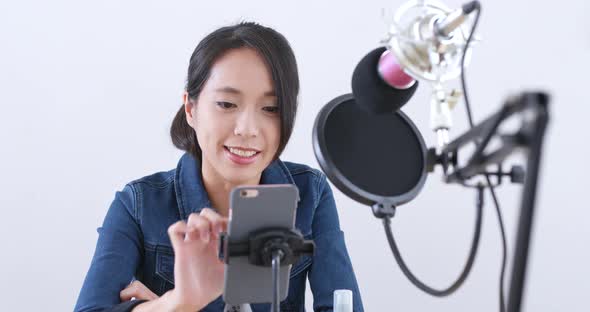 Young woman chatting on cellphone with live stream 