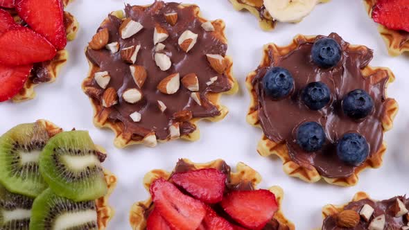 Rotating Background of Appetizing Sweet Wafers with Chocolate Spread Nuts and Fruits on a White