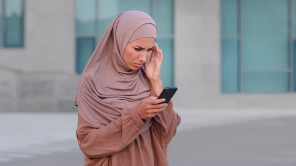 Muslim Islamic Girl Woman in Hijab Stands on Street Outdoors City Uses Mobile Phone Looks at