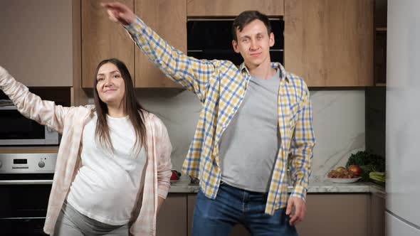 Young Future Parents Dance Together in Kitchen Smiling