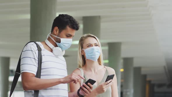 Caucasian couple on the go wearing a coronavirus covid19 mask and using phone