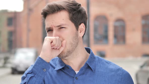 Sick Young Man Coughing while Standing Outdoor