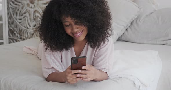 Beautiful Black Mixed Female Dreaming Relaxing Alone at Home Lying Bed with Smartphone