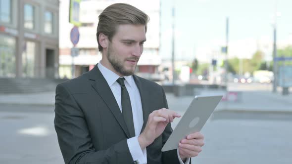 Businessman Celebrating Online Win on Tablet Outdoor