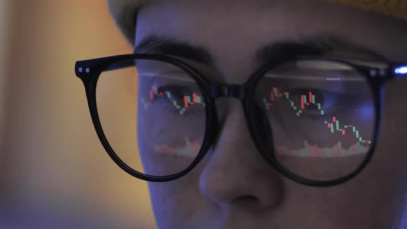 Closeup of a Young Woman Trader in Hat Wearing Eyeglasses Looking at a Computer Screen with Trading