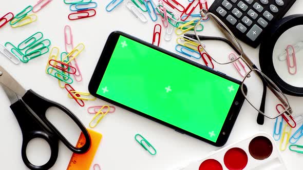 school supplies on a white background, in the center of the phone with a green screen, copy space