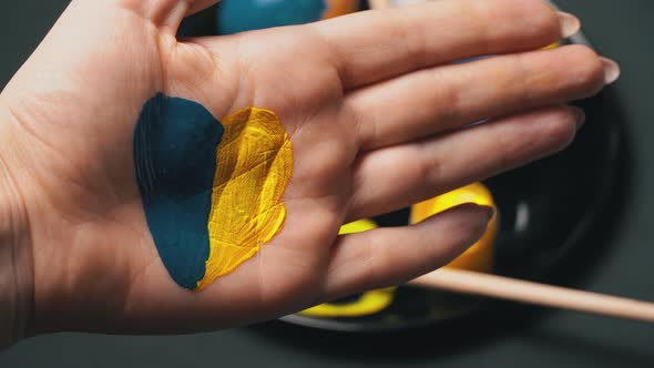 Painted Female Hand in YellowBlue Color on the Background of Easter Eggs