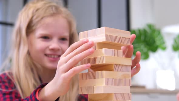 Children Playing Wooden Block Removal Tower Game at Home
