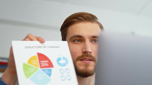 Young man showing infographic via video call with colleagues at home