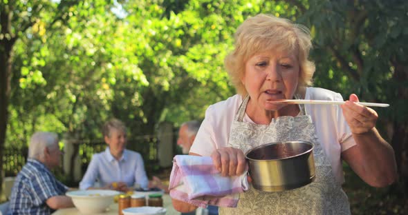 Senior woman tasting jam in garden