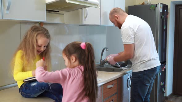 Father Washing Dishes in the Kitchen with His Little Girls