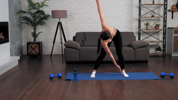 Young Fit Woman in Sportswear Doing Warmup Before Workout on Yoga Mat at Home