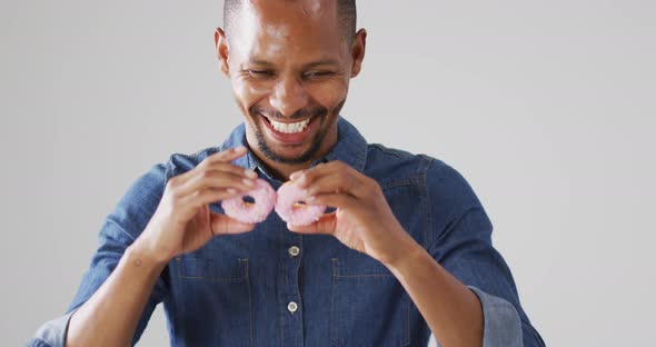 Video of biracial man holding donuts over white background