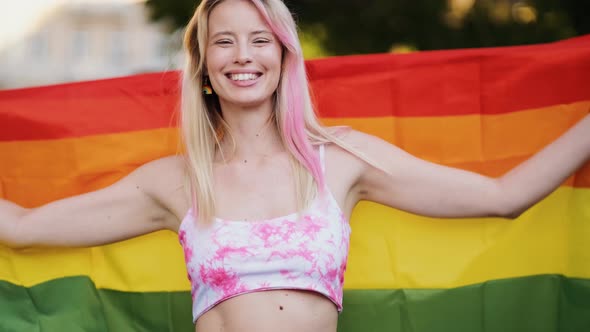 A woman dancing wrapped in a colorful flag during pride gay parade