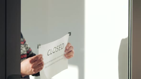 Man Hanging a Sign Closed on the Glass Door