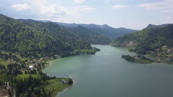 Aerial Panning of Landscape of lake in valley with mountains and blue skies