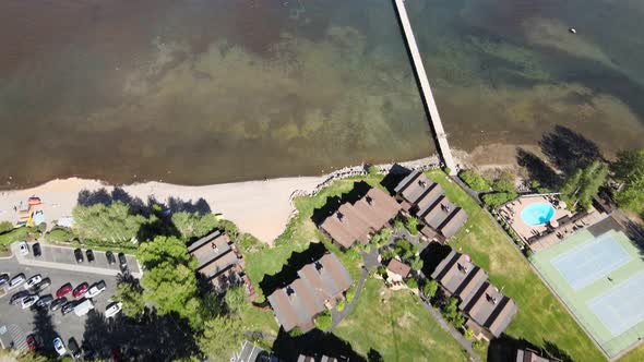 aerial drone footage of a Community center on the shore of Lake Tahoe. Long pier to deep water.