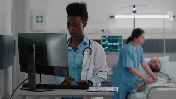 Front View of Afro American Doctor Typing Medical Expertise on Computer