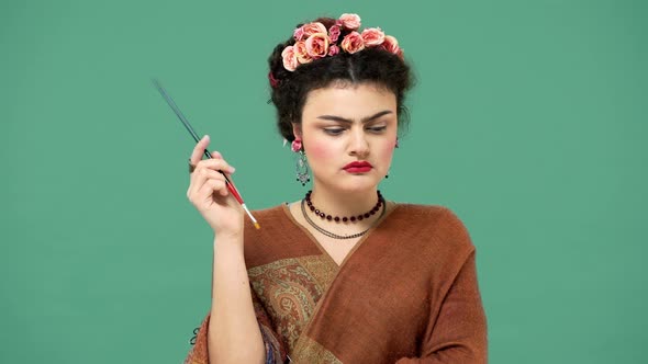 Fashion Portrait of Brunette Mexican Woman As Famous Celebrity Frida Kahlo Holding Paint Brush and