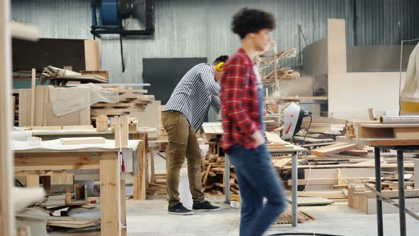 Woodworker Busy Sawing Wood with Circular Saw Standing in Workshop