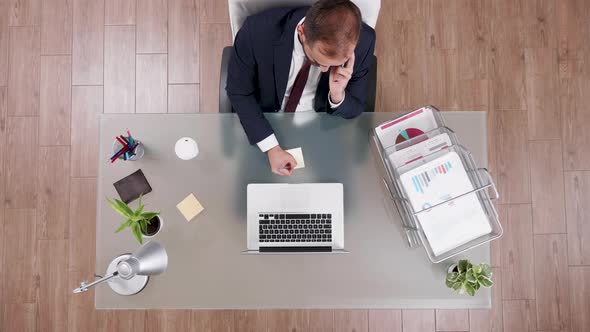 Top View of Businessman in Suit Talking on the Phone and Making Notes