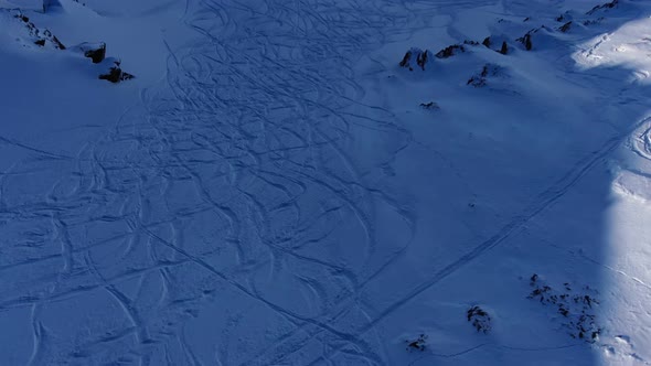 Men Silhouettes Ski on Snowy Mountain Slope Under Blue Sky