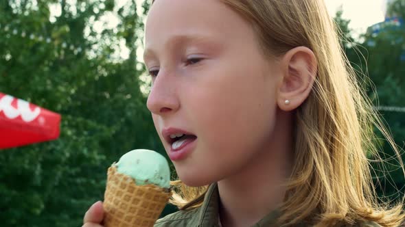 Blonde Teen Girl Licks a Delicious Scoop of Ice Cream in a Waffle Cone at the Sunday Fair