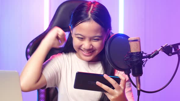 Asian Kid Girl Playing Video Game With Mobile Phone Then Celebrating While Live Stream alt