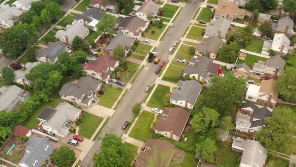An aerial shot over a suburban neighborhood on a cloudy day. The camera dolly in, tilted down over t