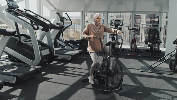 Woman in Hijab Cycling at Gym