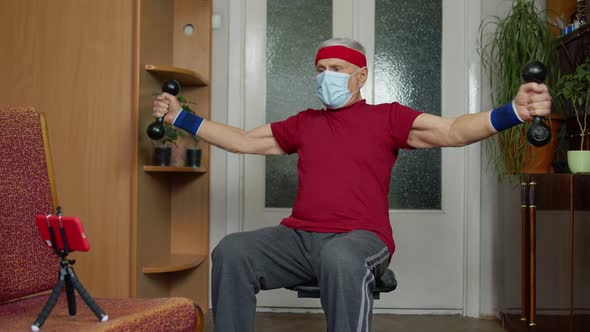 Senior Elderly Caucasian Man Making Weightlifting Dumbbells Exercising at Home During Coronavirus