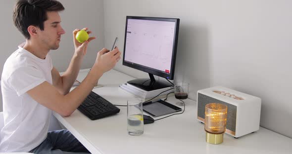 Businessman Using Smartphone while Sitting at His Desk, He Laughs and Smiles at Something Funny