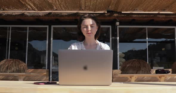 woman sitting on Hotel Sea Resort Bar enjoying sunset and working remotely on Laptop Computer