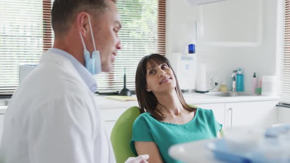 Portrait of smiling caucasian male dentist with female patient at modern dental clinic