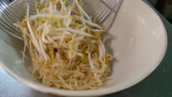 Close-Up Footage of Chef Adding Egg Noodles and Bean Sprouts into Bowl